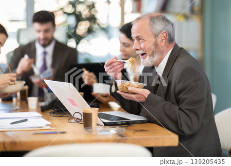 Lunch break - mature man eating noodles with colleagues in modern office Lunch break - mature man eating noodles with colleagues in modern office 139205435