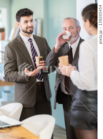 Coffee break - men and young woman drink coffee and chat lively with each other in modern office 139205454