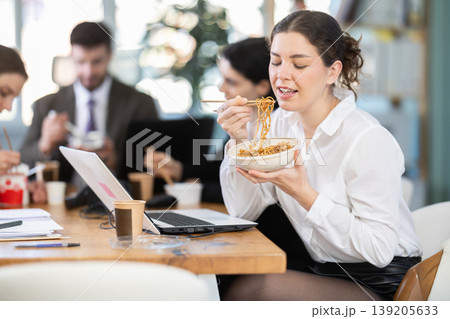Lunch break - woman eating noodles with colleagues in modern office Lunch break - woman eating noodles with colleagues in modern office 139205633