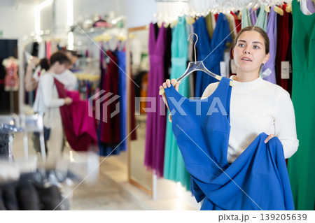 Young woman choosing dress in store Young woman choosing dress in store 139205639