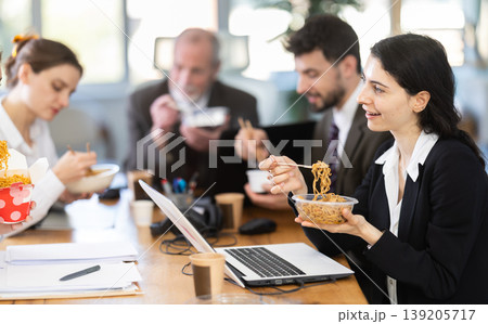 Lunch break - woman eating noodles with colleagues in modern office Lunch break - woman eating noodles with colleagues in modern office 139205717