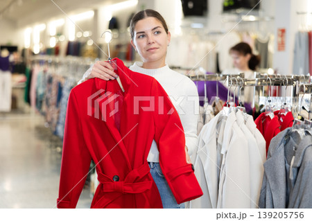 Young girl choosing unicolorous coat in clothing shop Young girl choosing unicolorous coat in clothing shop 139205756