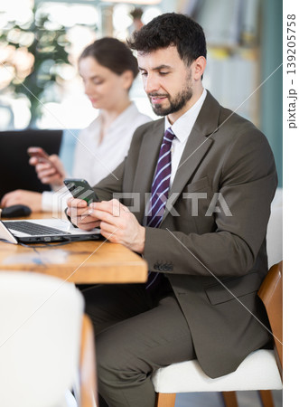 Man scrolls feed and passes time on social media. Bored staff on smartphone in background 139205758