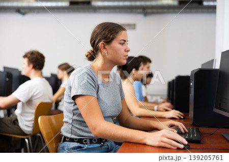 Side view on diligent college girl studying using pc in computer class Side view on diligent college girl studying using pc in computer class 139205761