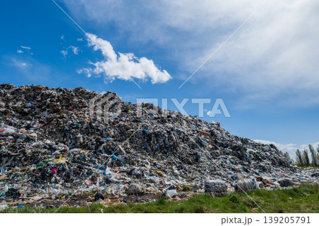 A large garbage dump is seen with heaps of waste under a blue sky, illustrating pollution challenges near a city A large garbage dump is seen with heaps of waste under a blue sky, illustrating pollution challenges near a city 139205791