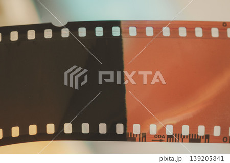 Analog film strip with exposed frames, negative and developed sections on light background, sprocket holes, color contrast, film texture. Film cinema production archive element Analog film strip with exposed frames, negative and developed sections on light background, sprocket holes, color contrast, film texture. Film cinema production archive element 139205841