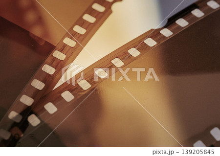 Close up of film strip negative frames on light surface, perforation edges, film strip detail, archive scanning. Natural background of film strip pattern, celluloid texture for cinema media design Close up of film strip negative frames on light surface, perforation edges, film strip detail, archive scanning. Natural background of film strip pattern, celluloid texture for cinema media design 139205845