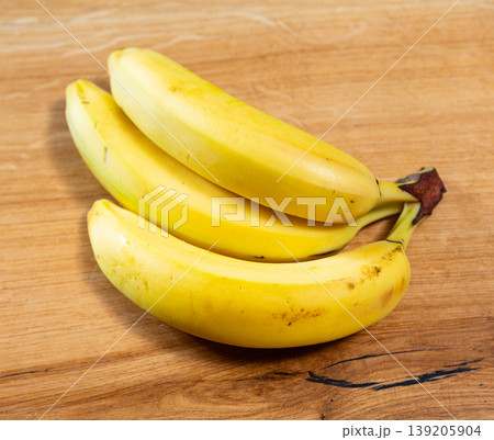 Three ripe bananas lie on wooden surface Three ripe bananas lie on wooden surface 139205904