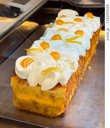 Rectangular sponge cake topped with whipped cream and fruit jelly decorations. Bakery product display, dessert preparation, pastry craft, and confectionery presentation. Rectangular sponge cake topped with whipped cream and fruit jelly decorations. Bakery product display, dessert preparation, pastry craft, and confectionery presentation. 139205926