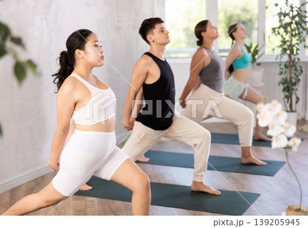 Young people doing a warrior yoga pose. 139205945