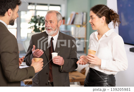 Coffee break - men and young woman drink coffee and chat lively with each other in modern office 139205981