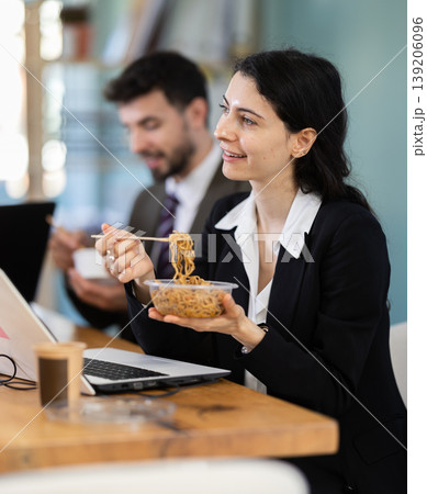 Lunch break - woman eating noodles with colleagues in modern office Lunch break - woman eating noodles with colleagues in modern office 139206096