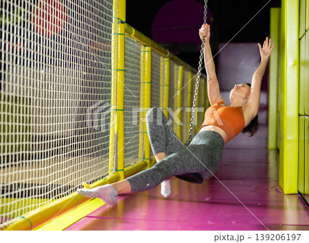 Woman enjoying riding zip line in colorful indoor amusement center Woman enjoying riding zip line in colorful indoor amusement center 139206197