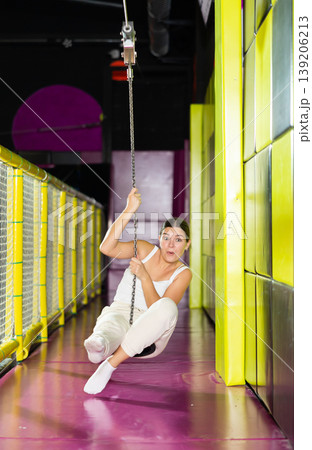 Cheerful young girl riding zip line in indoor amusement center 139206213