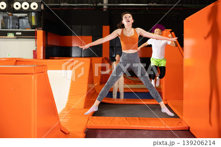 Middle-aged woman practice jumping on trampolines at trampoline center Middle-aged woman practice jumping on trampolines at trampoline center 139206214
