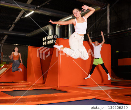 Girl acrobatic athlete jumping and exercising on trampoline indoors, modern hobby and fitness concept Girl acrobatic athlete jumping and exercising on trampoline indoors, modern hobby and fitness concept 139206239