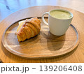 Croissant sandwich with cheese and ham served with green latte on tray. Breakfast meal, cafe serving, beverage pairing, and quick eating routine with simple ingredients. 139206408