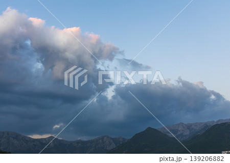 Dramatic Storm Clouds Gathering Over Mountain Range at Dusk With Pink Highlighted Edges 139206882