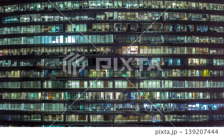 Working evening in glass office building with numerous offices with glass walls and windows timelapse 139207444