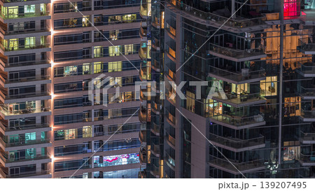 Rows of glowing windows with people in apartment building at night. Rows of glowing windows with people in apartment building at night. 139207495