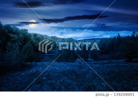 landscape by the lake at night. full moon over deciduous forest near the glacial lake. mysterious view of fantasy forest of carpathian mountains in spring. dark sky. hiking and tourism background landscape by the lake at night. full moon over deciduous forest near the glacial lake. mysterious view of fantasy forest of carpathian mountains in spring. dark sky. hiking and tourism background 139208001