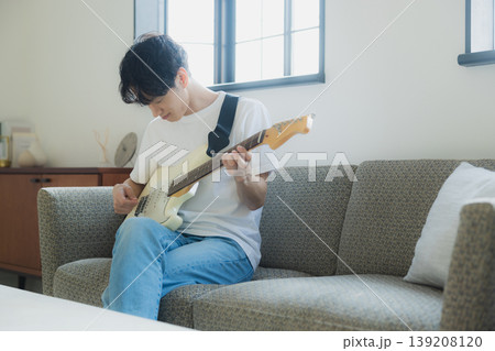 ソファーでギターを弾く若い男性 139208120
