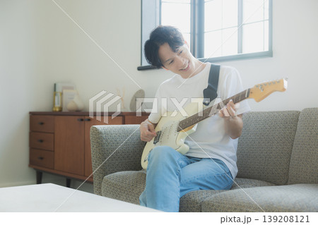 ソファーでギターを弾く若い男性 ソファーでギターを弾く若い男性 139208121