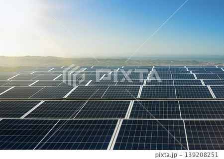 Massive field of photovoltaic solar panels basking in sunlight on a coastal hillside, representing clean sustainable green energy production for the future Massive field of photovoltaic solar panels basking in sunlight on a coastal hillside, representing clean sustainable green energy production for the future 139208251