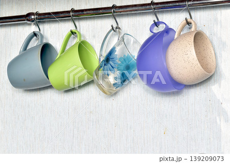 Ceramic and glass mugs hang on the wall. Ceramic and glass mugs hang on the wall. 139209073