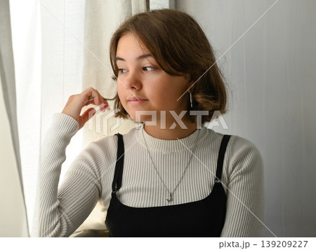 Portrait of a girl at the window in thought 139209227