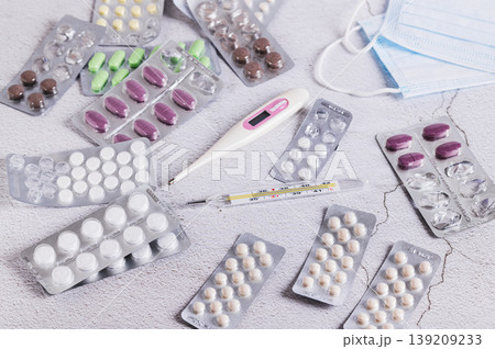 Blister packs with pills, medical masks and thermometers on the table 139209233