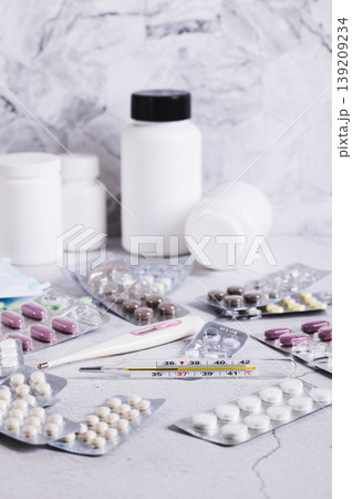 Thermometers and a variety of medicines for treatment on the table vertical view Thermometers and a variety of medicines for treatment on the table vertical view 139209234