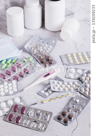 Blister packs with pills, medical masks and thermometers on the table vertical view Blister packs with pills, medical masks and thermometers on the table vertical view 139209235