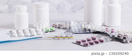 Thermometers and a variety of medicines for treatment on the table web banner 139209240