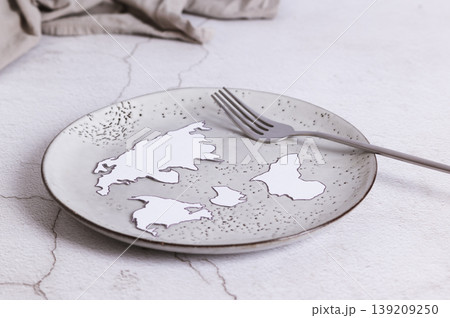 An empty plate without food, a fork and paper continents on the table An empty plate without food, a fork and paper continents on the table 139209250