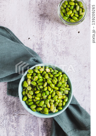 Frozen edamame soybeans on a plate and in a jar on a table top and vertical view Frozen edamame soybeans on a plate and in a jar on a table top and vertical view 139209265