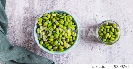 Frozen edamame soybeans on a plate and in a jar on a table top view web banner Frozen edamame soybeans on a plate and in a jar on a table top view web banner 139209266