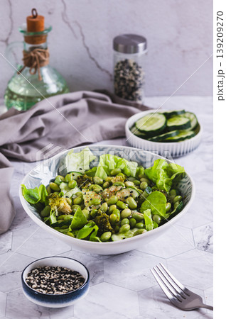 Green salad with edami beans, cucumber, broccoli and lettuce in a bowl on the table vertical view Green salad with edami beans, cucumber, broccoli and lettuce in a bowl on the table vertical view 139209270