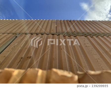 Clay hollow blocks with ribbed surface installed in wall construction under blue sky view from below. Construction, masonry, building materials, architecture, wall building 139209935