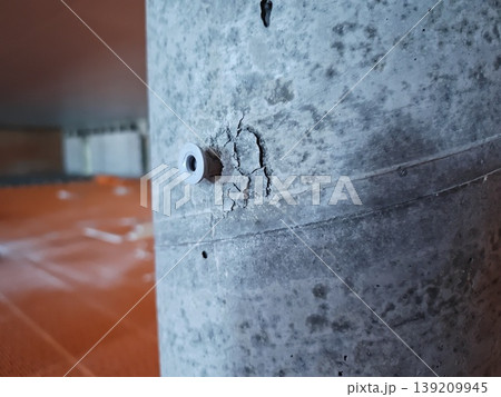 Close up of cracked concrete column with anchor fastener inside livestock building with plastic slatted flooring system. Construction detail, agriculture facility Close up of cracked concrete column with anchor fastener inside livestock building with plastic slatted flooring system. Construction detail, agriculture facility 139209945
