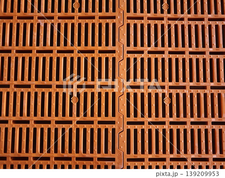 Orange plastic slatted floor panels for pig housing with perforated grid pattern and modular interlocking design. Livestock farming, agriculture equipment, animal housing 139209953