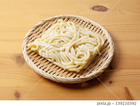 木のテーブルに置かれた竹ざるの上のゆでうどんのブロック 139210392