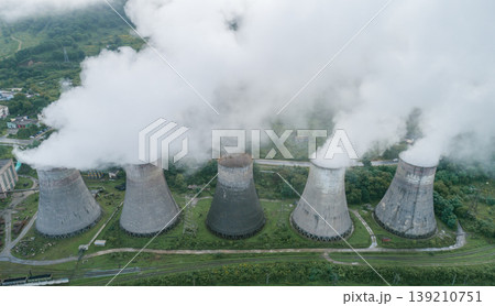 Industrial power plant with five massive cooling towers generating vast plumes of white steam into the air 139210751
