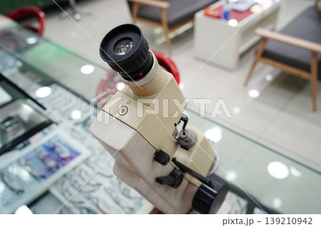 Vintage lensmeter device for measuring eyeglass lens power, professional optical equipment in optician shop or ophthalmology clinic. Vintage lensmeter device for measuring eyeglass lens power, professional optical equipment in optician shop or ophthalmology clinic. 139210942