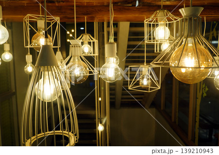 Group of decorative industrial pendant lights with glowing Edison bulbs, stylish modern interior lighting for cafe and home decor. Group of decorative industrial pendant lights with glowing Edison bulbs, stylish modern interior lighting for cafe and home decor. 139210943