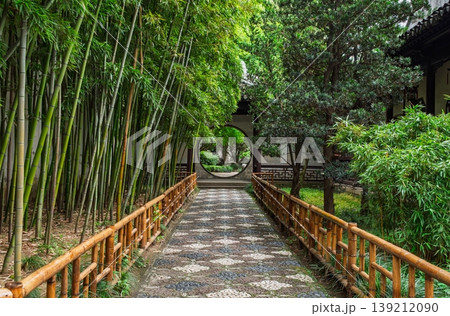 Bamboo lined path leading to a moon gate in a traditional Chinese garden in Suzhou, China Bamboo lined path leading to a moon gate in a traditional Chinese garden in Suzhou, China 139212090