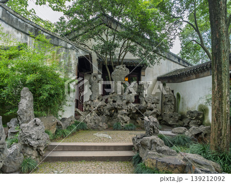 Classic Suzhou garden displaying traditional architecture, intricate rockwork, and vibrant bamboo plants Classic Suzhou garden displaying traditional architecture, intricate rockwork, and vibrant bamboo plants 139212092