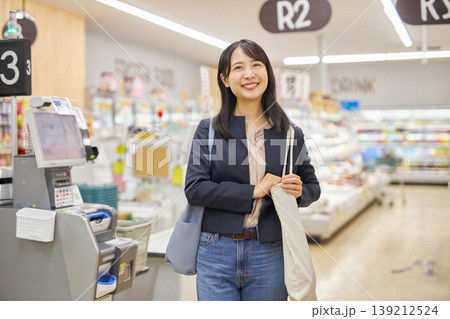 セルフレジで清算を済ませてエコバッグを肩に描ける若い女性 139212524