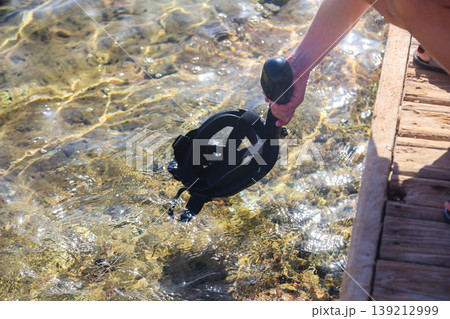 Woman cleaning her snorkeling mask in the clear blue sea, preparing for an exciting underwater adventure and enjoying the beauty of marine life Woman cleaning her snorkeling mask in the clear blue sea, preparing for an exciting underwater adventure and enjoying the beauty of marine life 139212999
