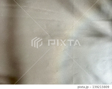 crumpled beige fabric texture shimmering under soft light with gentle folds and gradient shadows 139213809